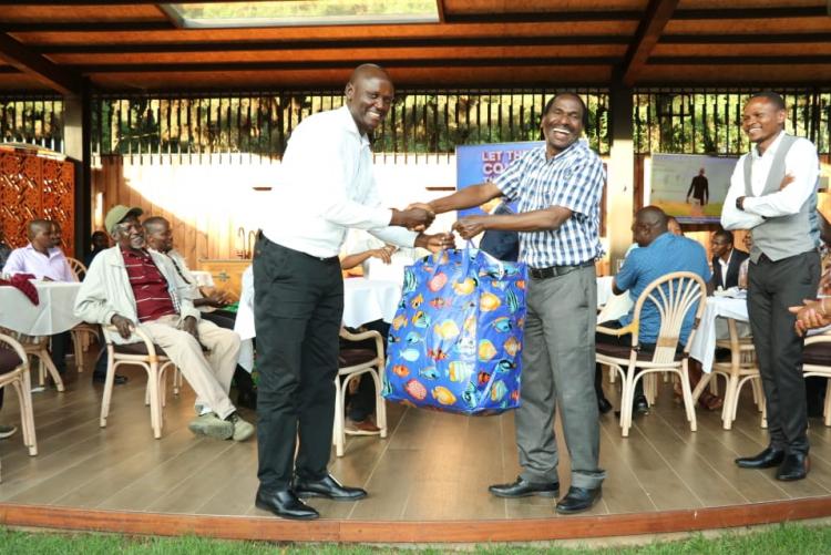 Dr. Nyete receiving a gift on behalf of Mr. Kyalo from the chairman Prof. Kamucha.
