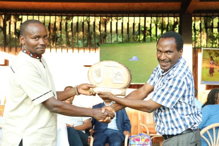 Mr. Rukenya  receiving a plaque on behalf of Mr. Muraba from the chairman Prof. Kamucha.